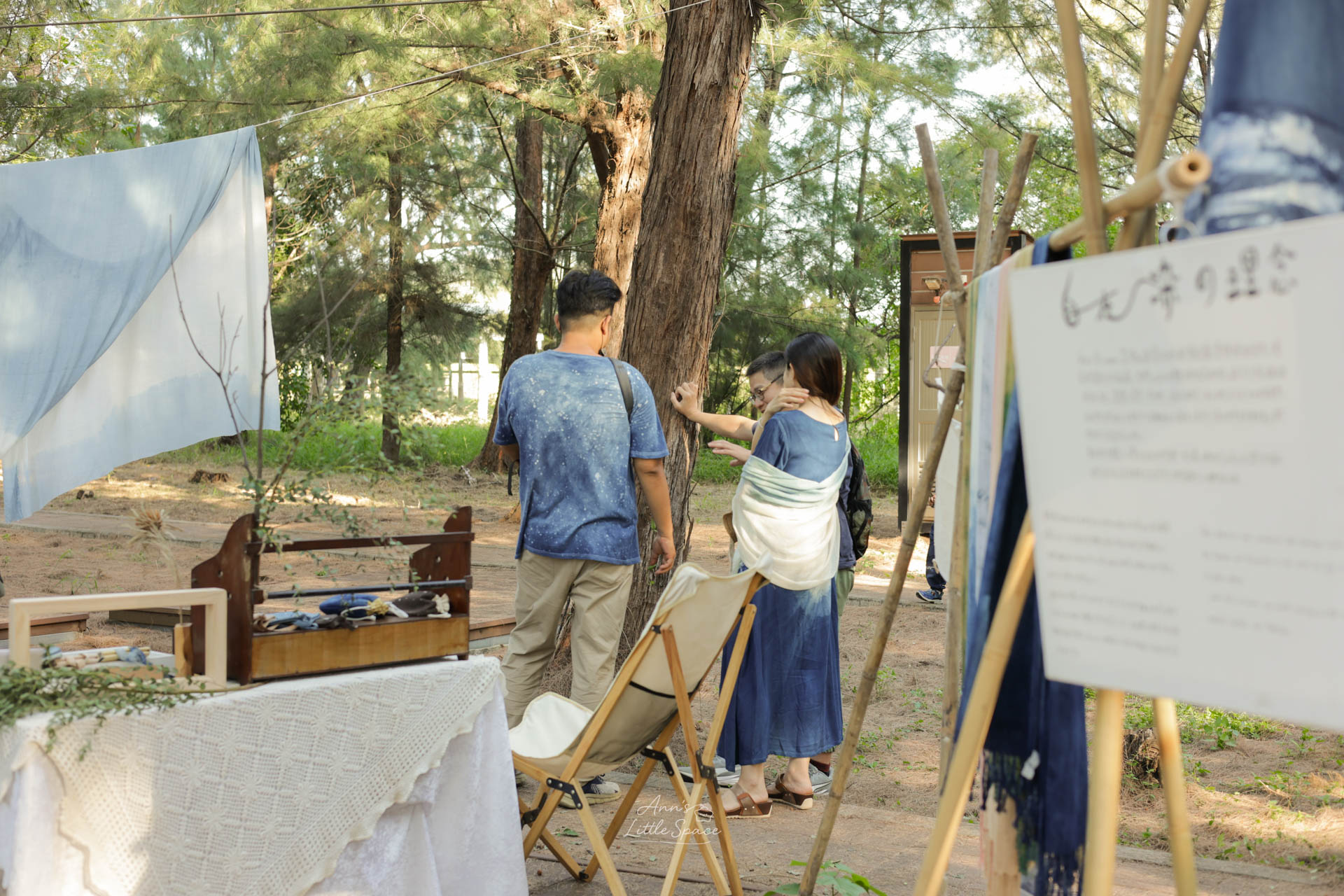 灰熊綠展中的藍染工藝展示區，民眾穿梭在懸掛的藍染布幔與木麻黃樹林間，呈現自然與傳統工藝結合的靜謐感｜by Ann's Little Space