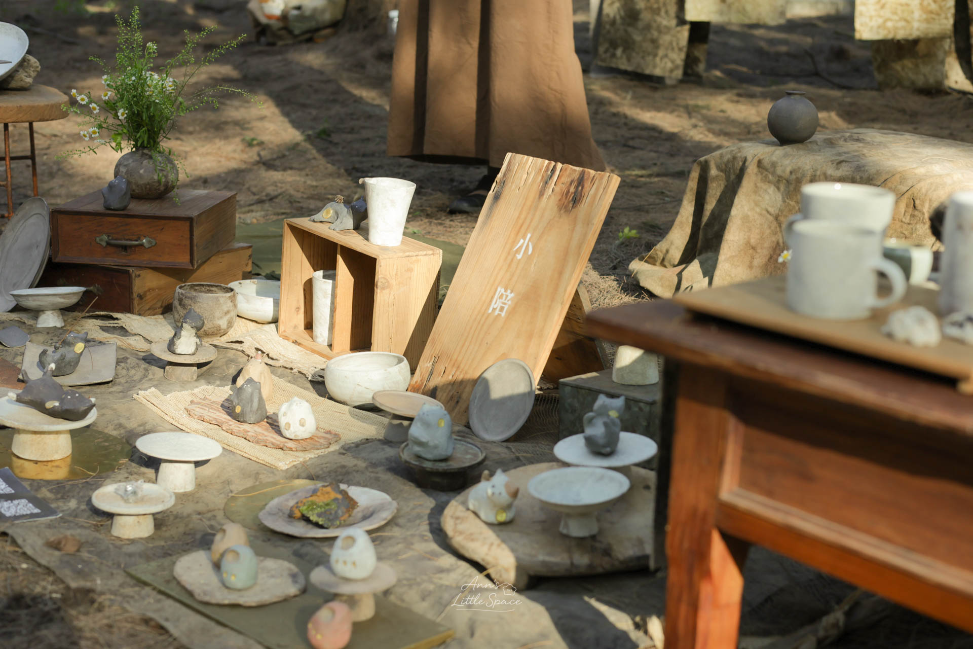 灰熊綠展中的手作陶器與小動物擺飾展示於木麻黃樹林間，木質器物與自然光影營造出溫柔靜謐的森林氛圍｜by Ann's Little Space